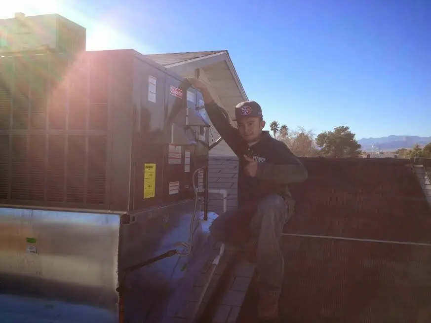 HVAC technician performing Heat Pump Repair on a rooftop unit in Taylorville